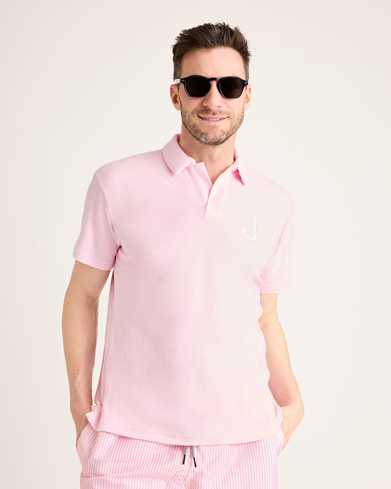 Man wearing a pink polo shirt and pants with sunglasses on a light pink background|Model: 5'11" wearing size L