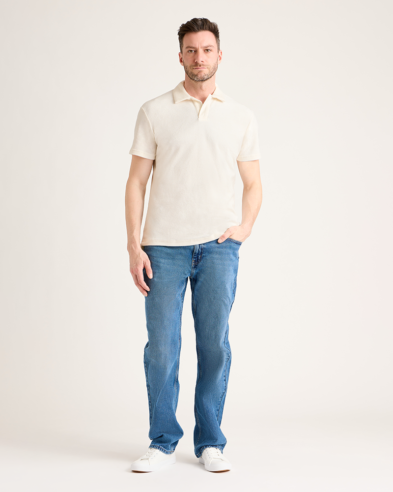 Man wearing a beige polo shirt and blue jeans on a white background|Model: 5'11" wearing size L