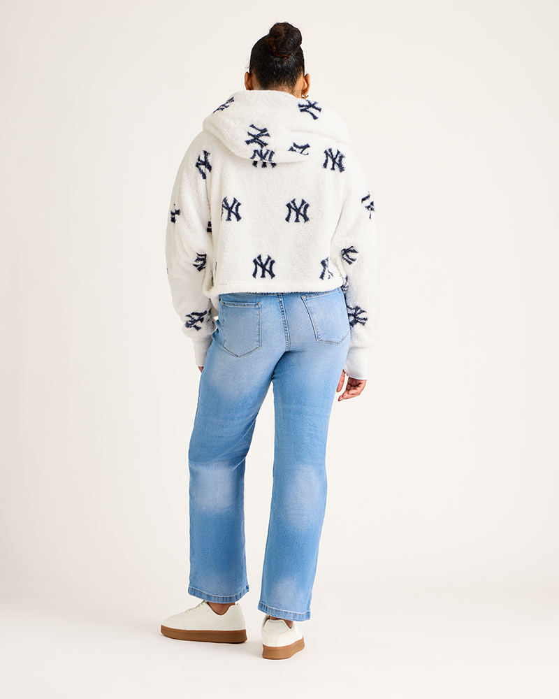 Person wearing a white hoodie with black patterns and light blue jeans on a white background|Model: 5'9" in size XS/S