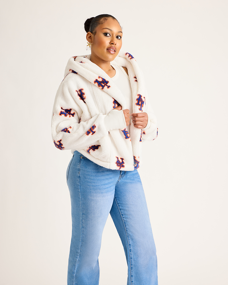 Woman wearing a white hoodie with colorful patterns and light blue jeans on a plain background|Model: 5'9" in size XS/S