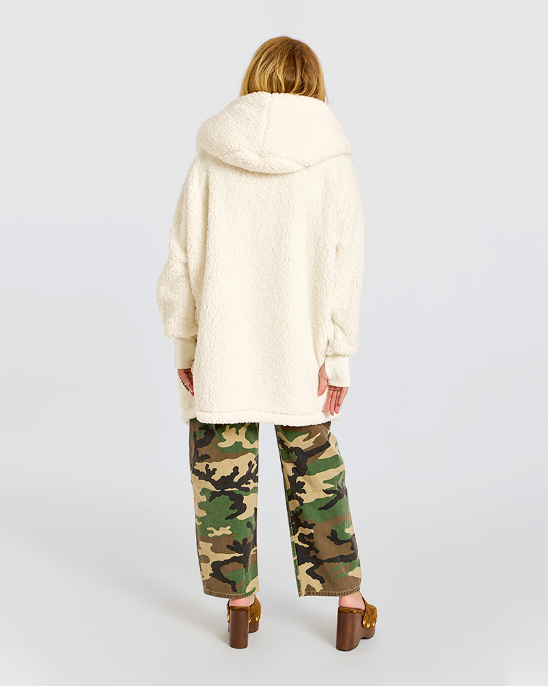 A woman shown from the back wearing a cream sherpa fleece hooded sweatshirt, green camouflage pants, and brown block-heel sandals against a light gray studio background.|Jill is 5'6" wearing size XS/S