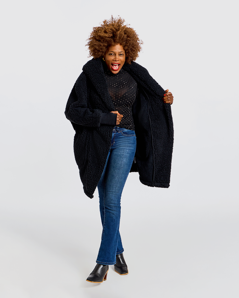 A woman modeling a black teddy-texture coat over a black top and blue jeans, standing against a light gray studio background.|Model is 5'7" wearing size XS/S