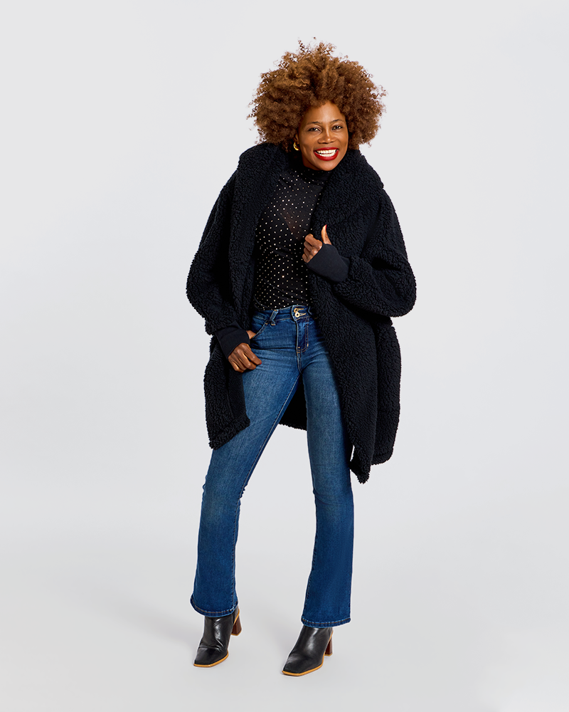 A woman modeling a black teddy coat over a black polka-dot top, blue jeans, and black ankle boots, photographed against a light gray studio background.|Model is 5'7" wearing size XS/S