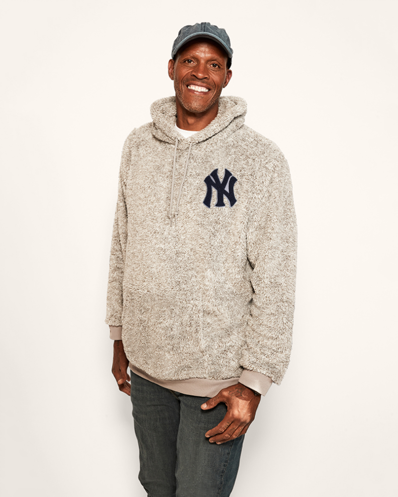 Man wearing a gray hoodie with a yankees logo on a white background