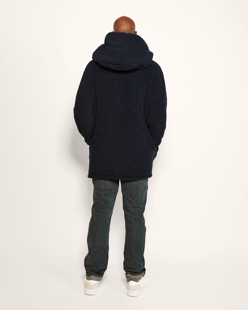 Person wearing a black hoodie and jeans from behind on a white background