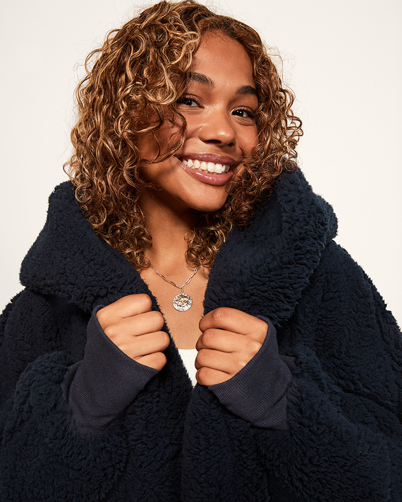 Person wearing a dark blue sherpa coat against a plain background