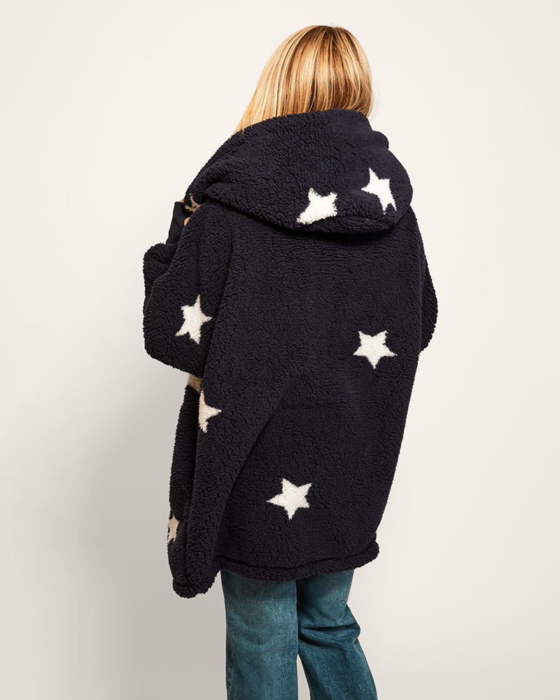 Person wearing a navy hoodie with white star patterns on a plain background