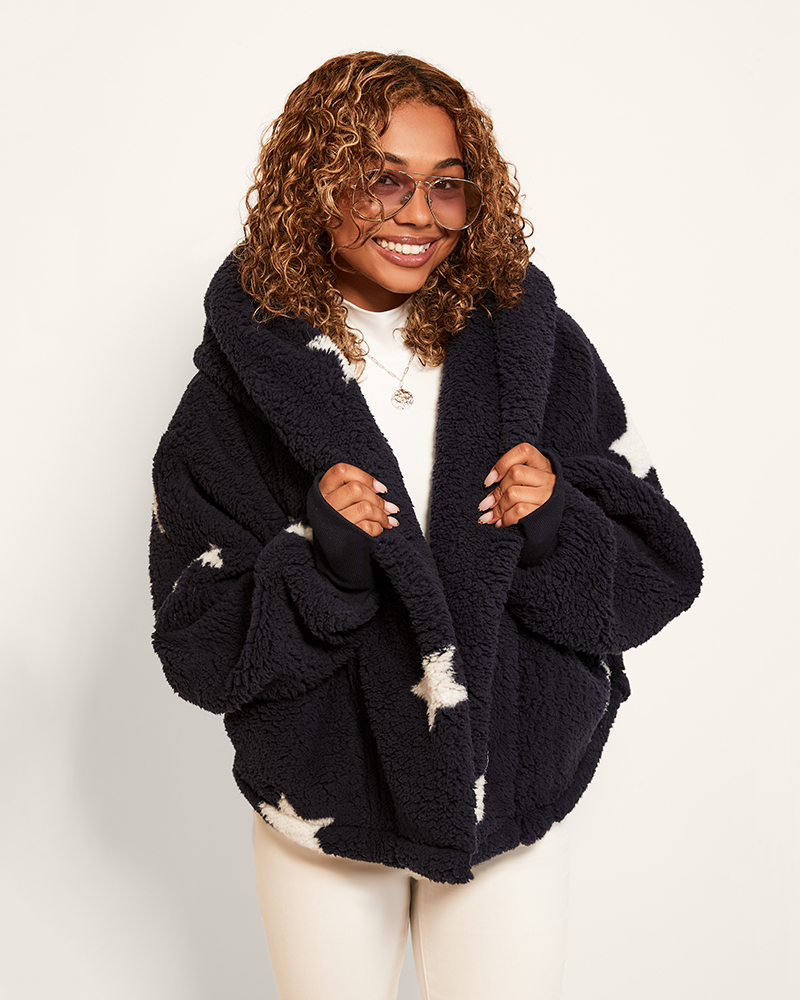 Person wearing a dark blue fleece jacket with star patterns on a white background