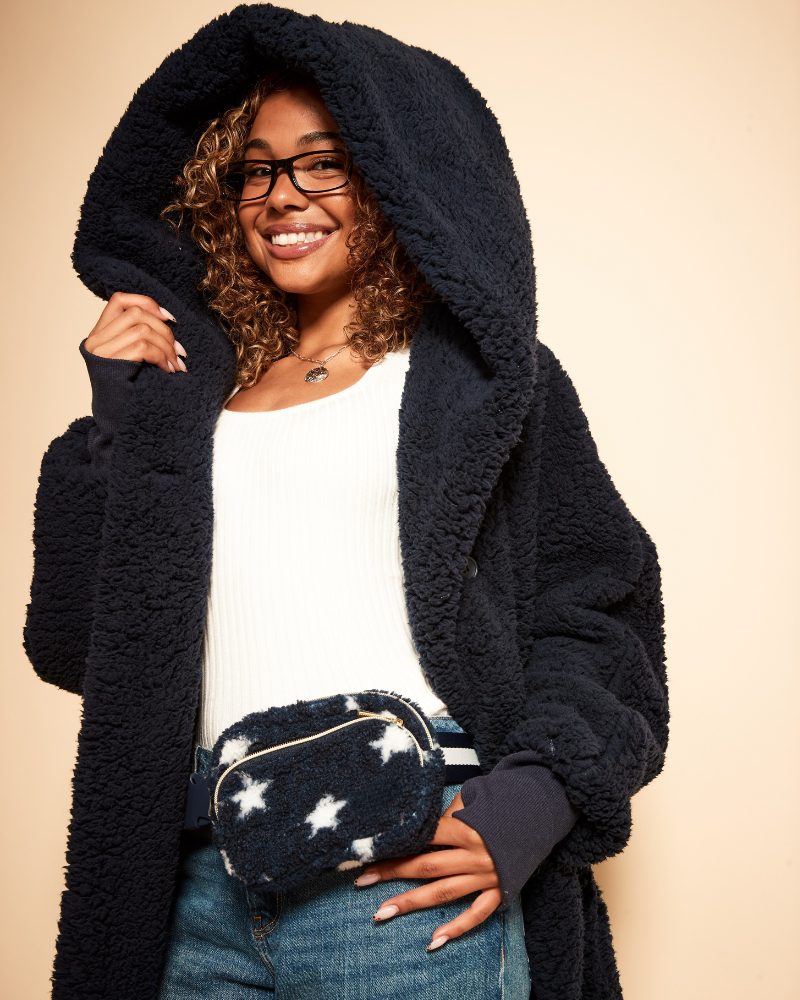 girl wearing navy sherpa lounger with navy and white star sherpa fanny pack on beige background