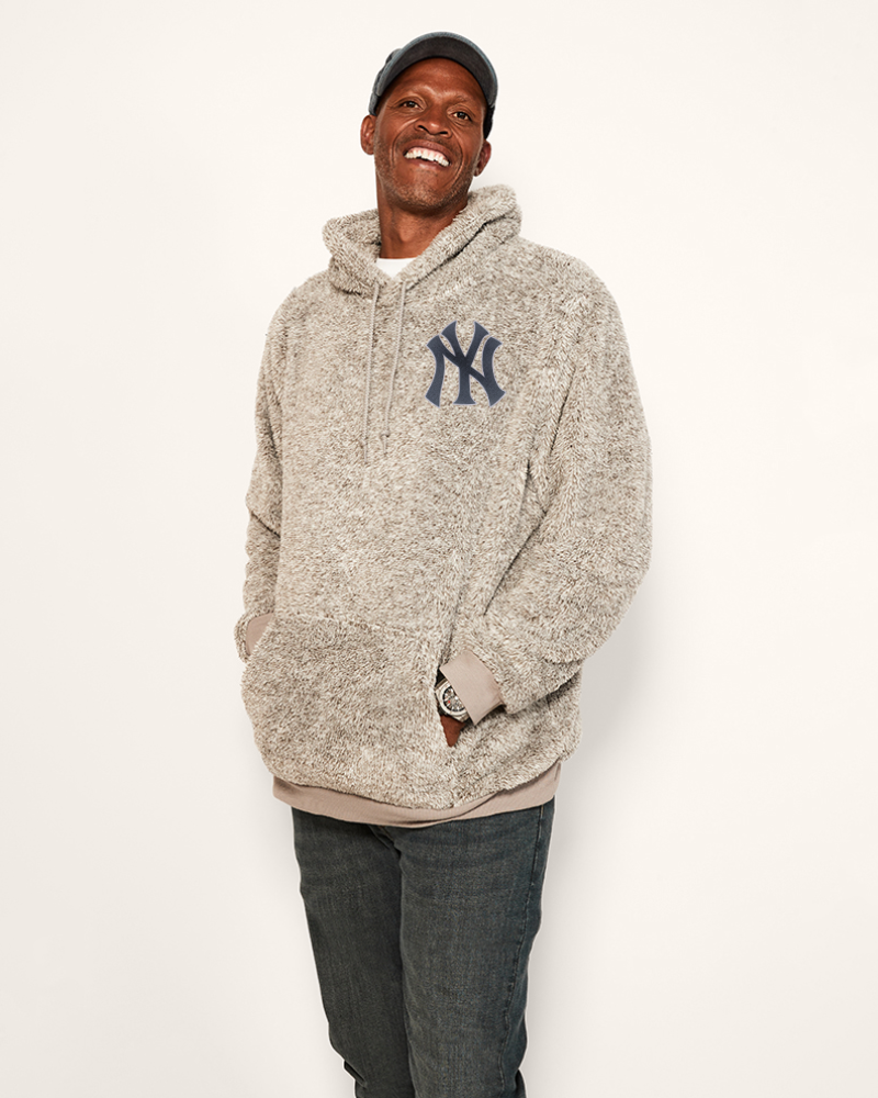 man wearing grey hoodie with chenille yankees logo patch in upper left