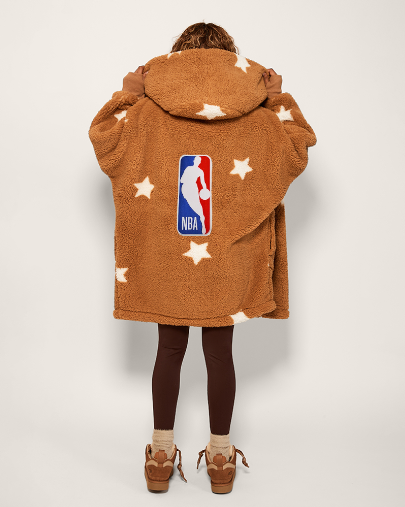 Person wearing a tan fleece jacket with NBA logo and star patterns on a white background