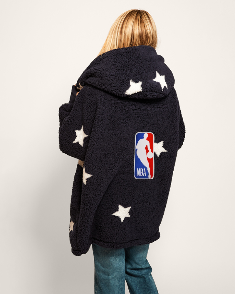 Person wearing a navy hoodie lounger with star patterns and NBA logo on a light gray background