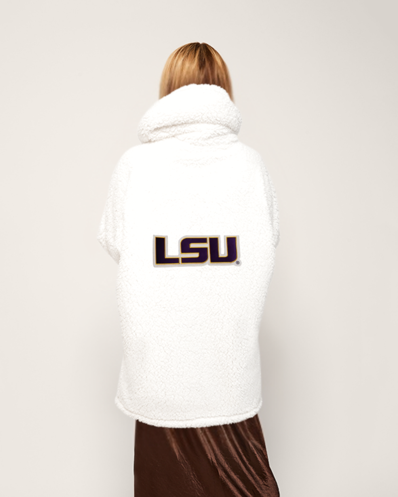 Person wearing a white sherpa jacket with LSU logo on a plain background