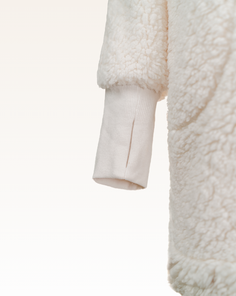 Close-up of a cream-colored sherpa jacket on a white background
