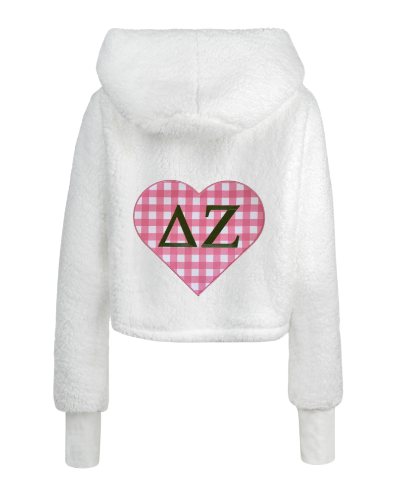 White fuzzy cropped hoodie with a pink gingham heart graphic on the back featuring the Greek letters Delta Zeta in black.