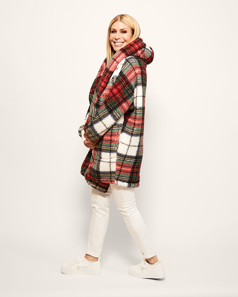Woman wearing a red and green plaid coat on a white background