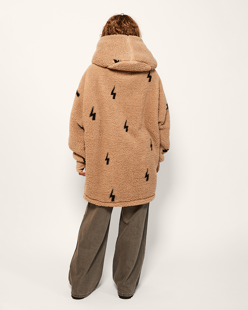 Person wearing a brown teddy coat with black patterns on a white background