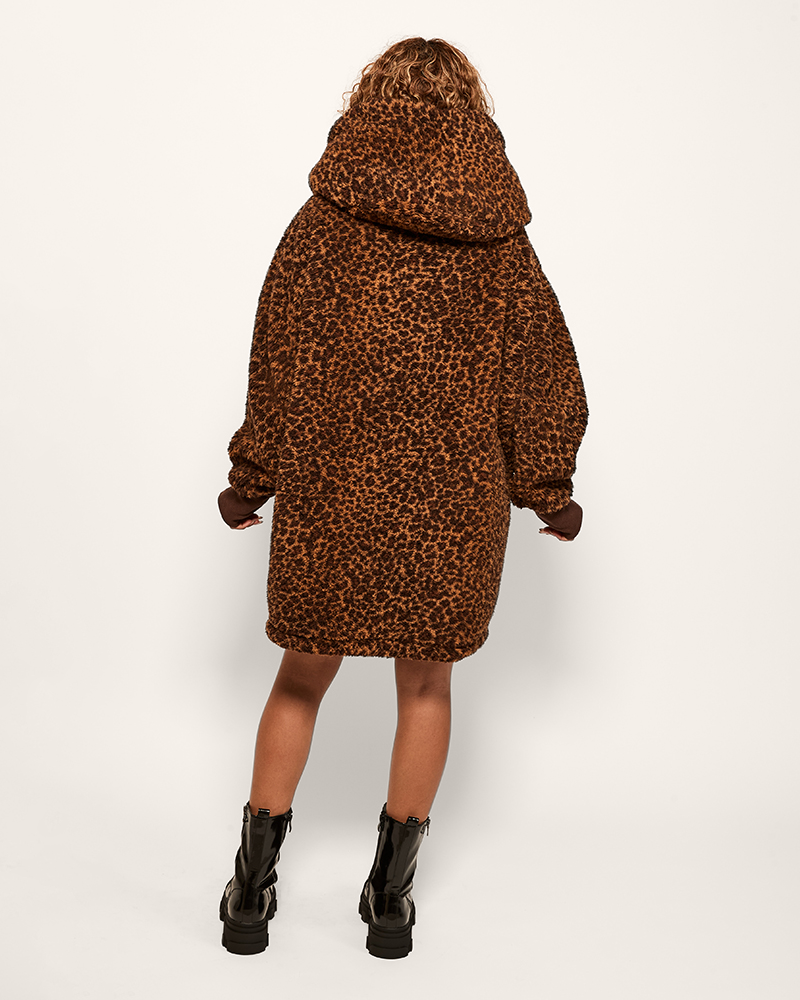person wearing leopard sherpa lounger over black top and skirt against light background