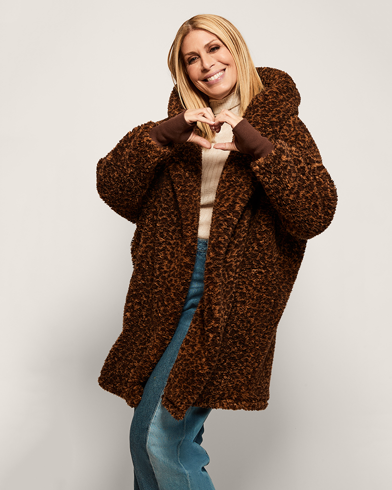 person wearing leopard sherpa lounger over black top and skirt against light background