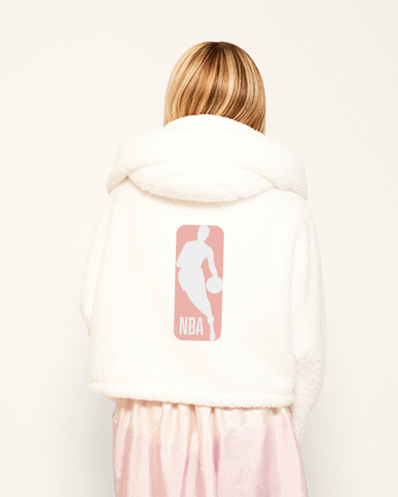 Person wearing a white hoodie with an NBA logo on the back, standing against a plain background.