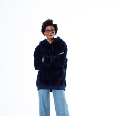 Girl in a cozy navy sherpa sweatshirt and jeans, arms crossed, wearing glasses with a casual, confident look.